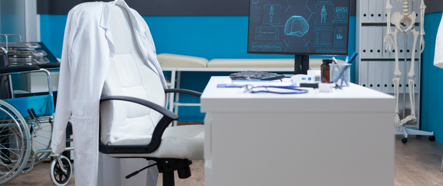 Ein Computer steht auf einem Tisch in einem leeren Arztzimmer während einer anatomischen Untersuchung. Auf dem Bildschirm ist die Knochenstruktur eines Patienten zu sehen, vermutlich eine Skelett-Radiographie. Das medizinische Arbeitsumfeld ist sauber und ordentlich, mit moderner Ausstattung zur Unterstützung von Gesundheitsdienstleistungen.